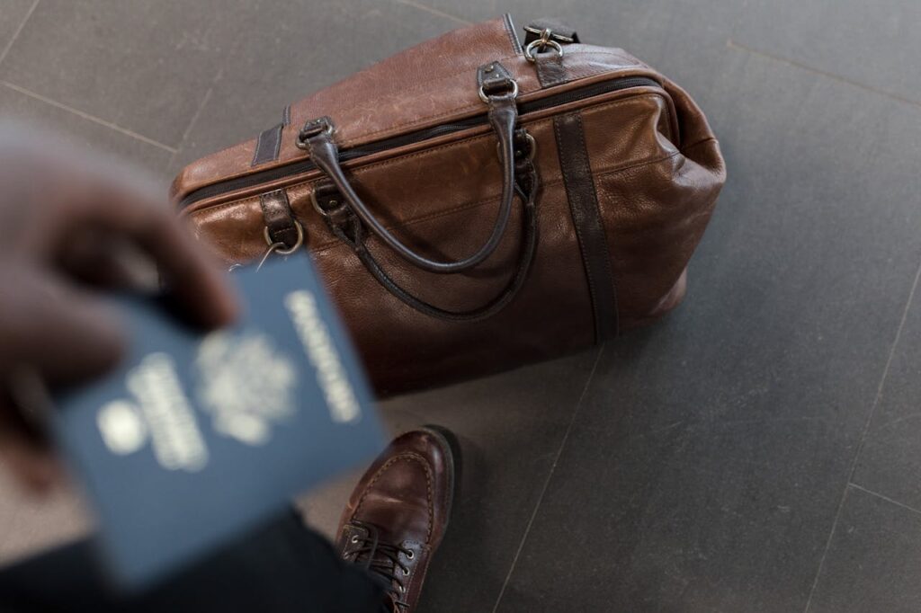 pexels-photo-1058959 Brown leather bag with passport in an airport setting, ideal for travel and fashion themes.